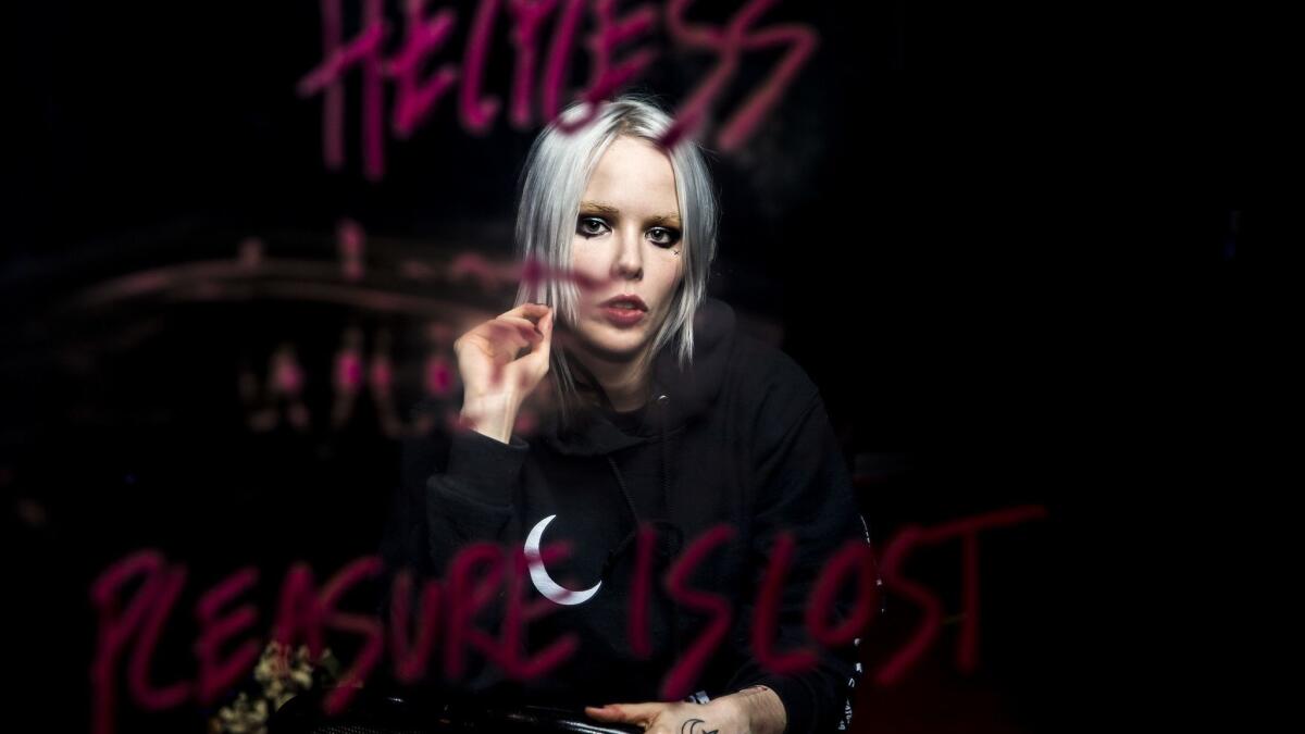 Alice Glass is reflected in a mirror with lipstick text for an earlier video project.
