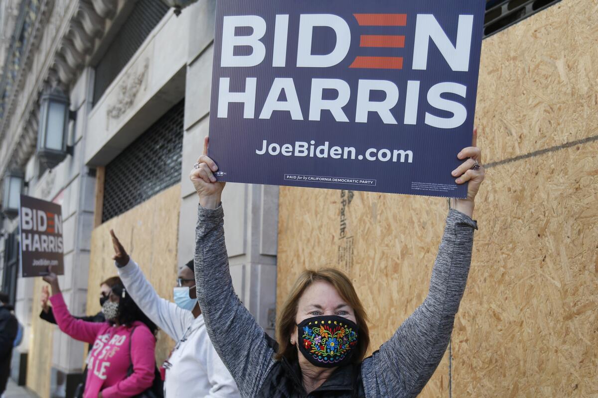 Unas personas celebran el triunfo del presidente electo Joe Biden y la vicepresidenta electa Kamala Harris en Los Angeles.