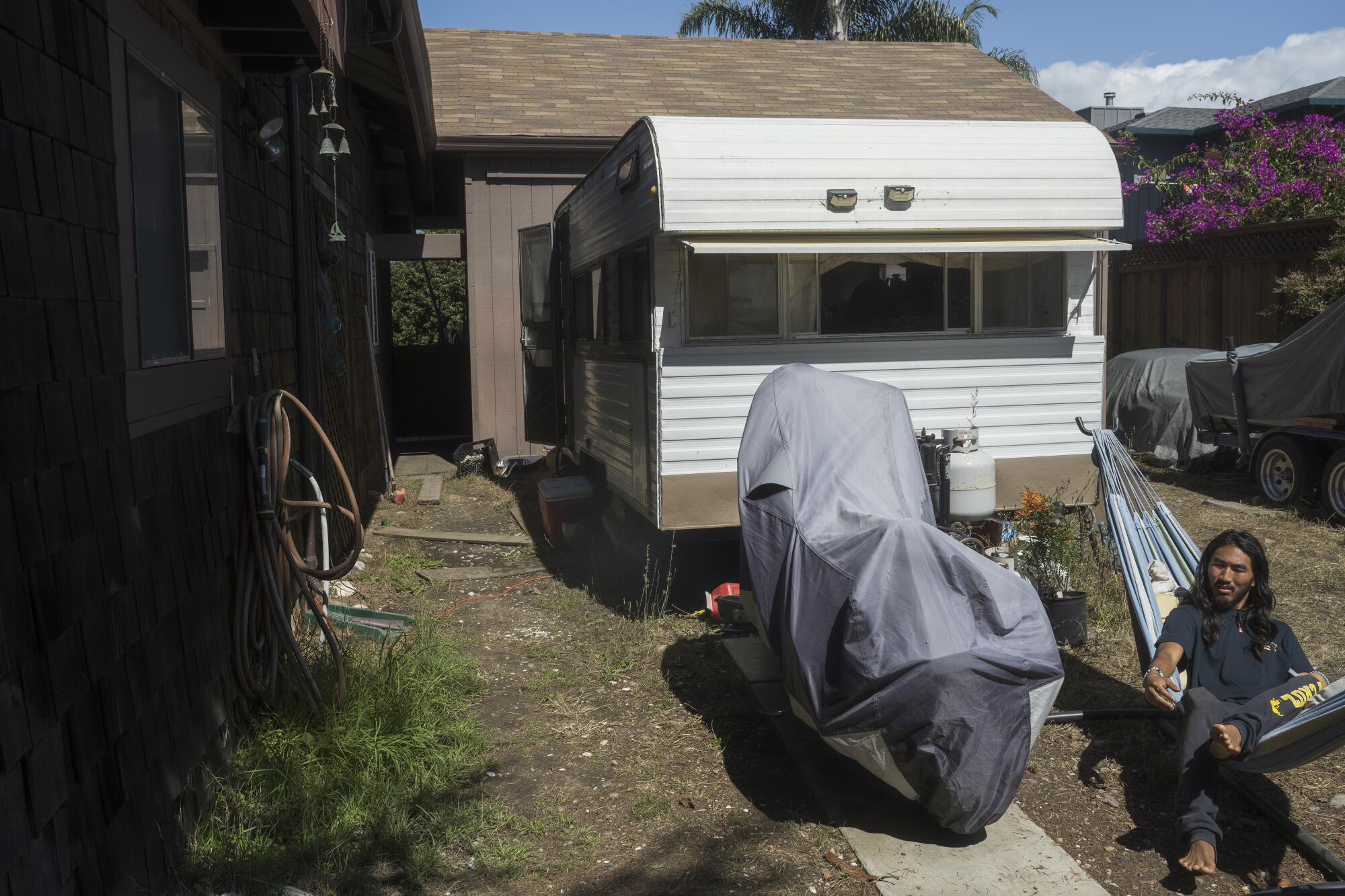 A man sits in a hammock outside a trailer