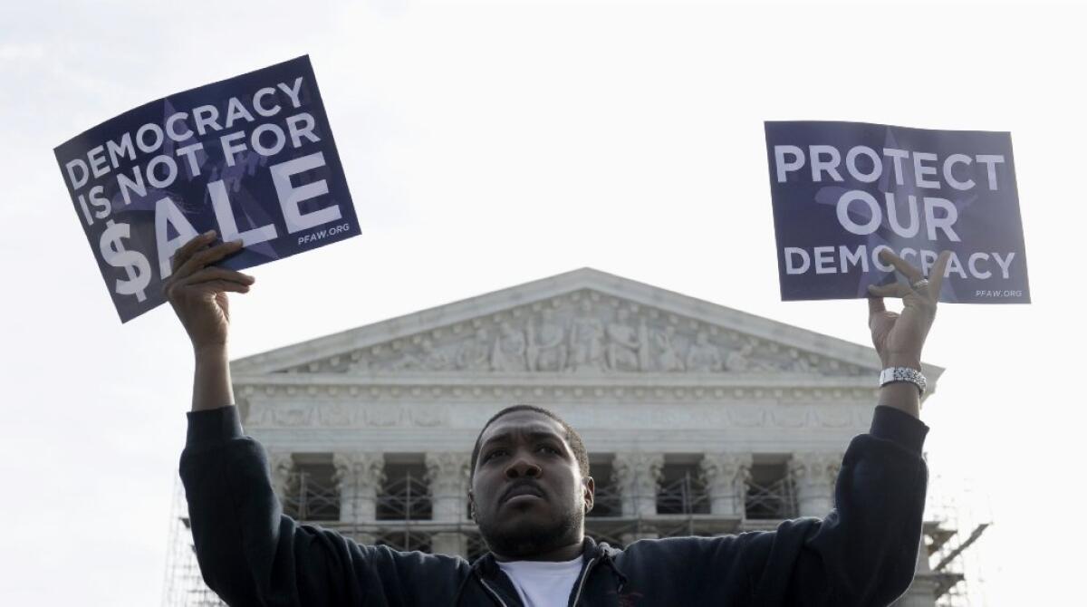 A protester stands outside the Supreme Court in Washington last October as the justices hear arguments on a case involving campaign finance.