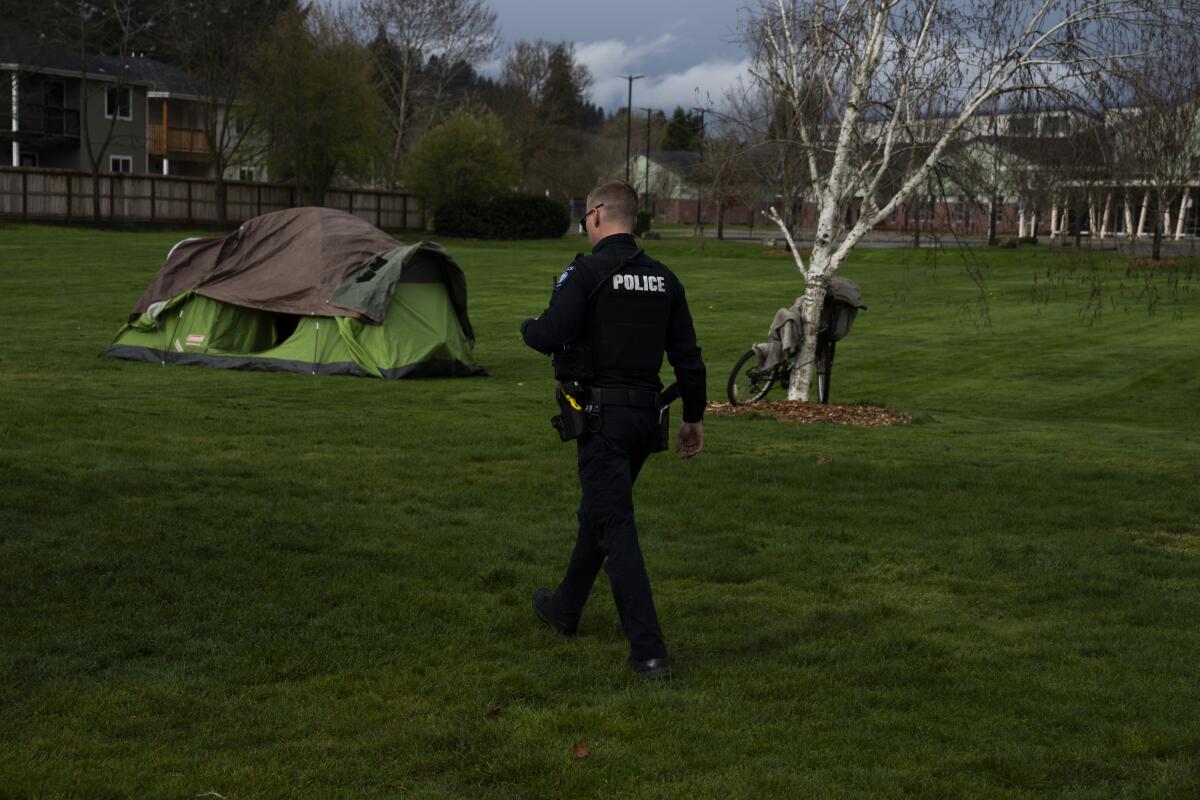 A Grants Pass, Ore., police officer checks on a homeless person camped at a public park3. 