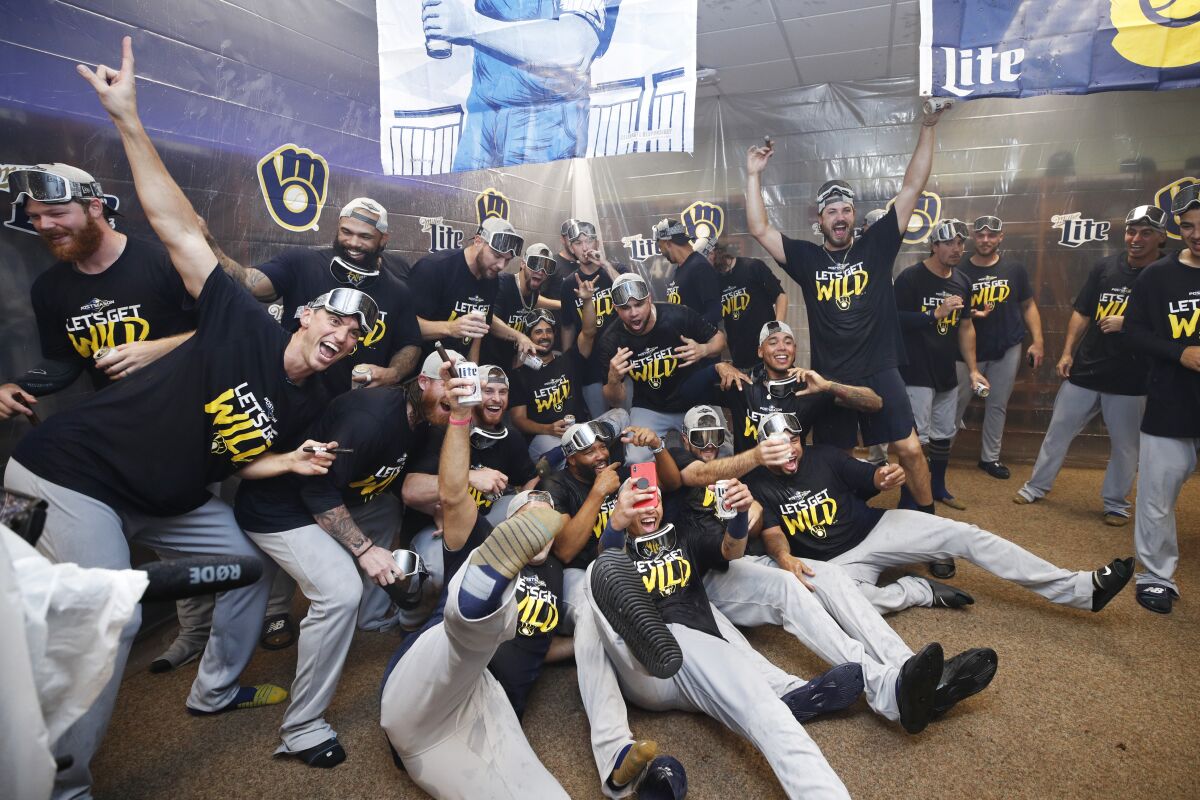 Milwaukee Brewers players celebrate in the clubhouse after clinching a playoff berth following a 9-2 win over the Cincinnati Reds on Wednesday.