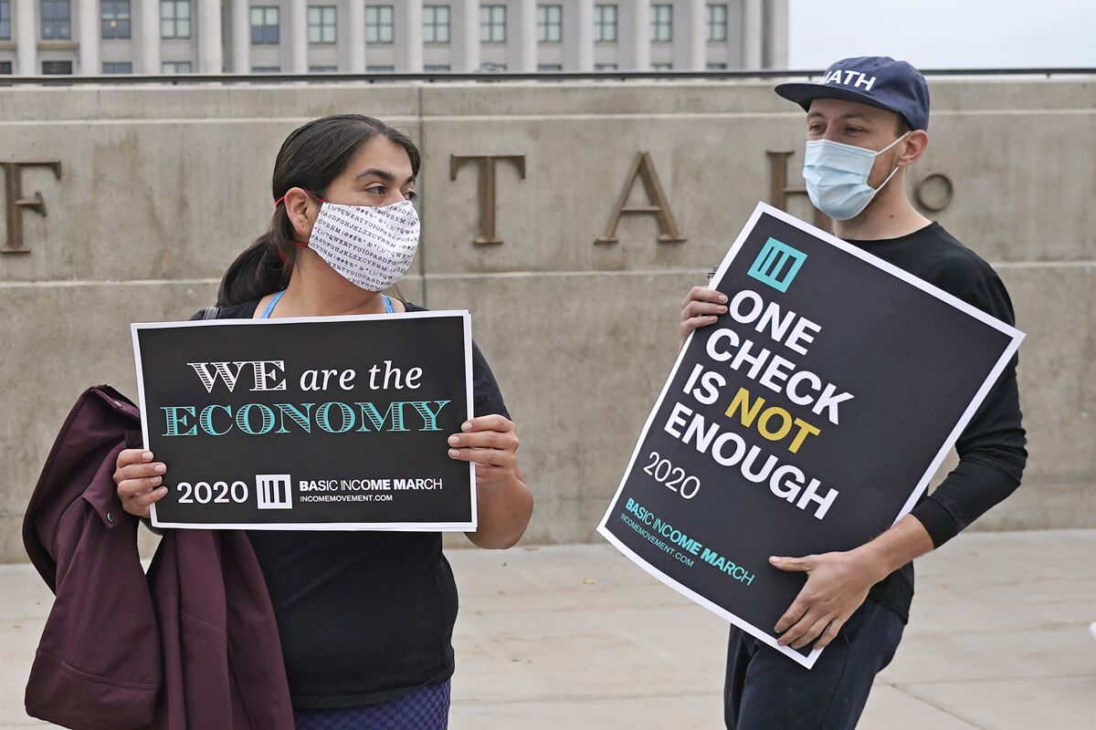 People hold signs reading "We are the economy" and "One check is not enough"