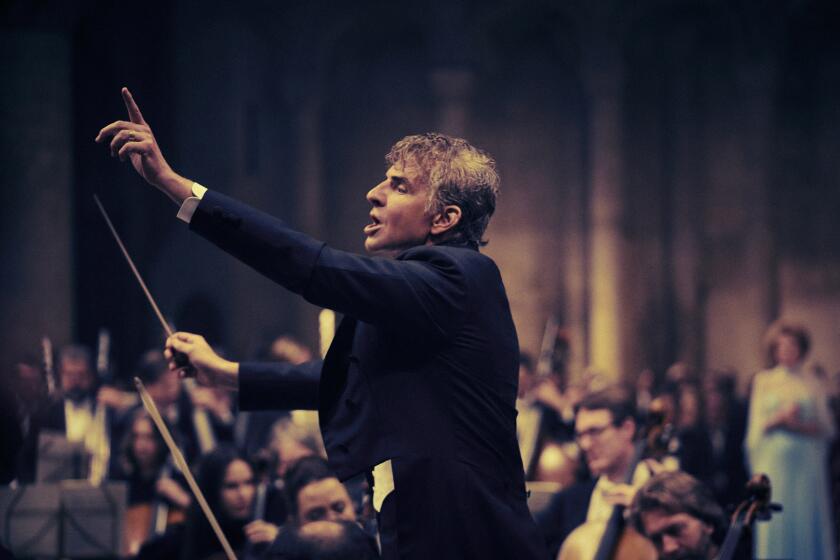 A man conducts an orchestra inside a cathedral.