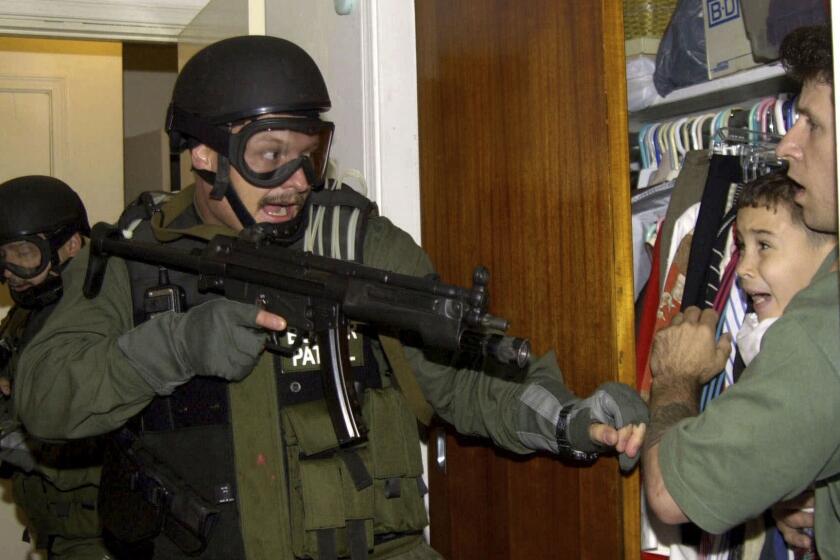 FILE - In this April 22, 200, file photo, by Associated Press photojournalist Alan Diaz, Elian Gonzalez is held in a closet by Donato Dalrymple, one of the two men who rescued the boy from the ocean, right, as government officials search the home of Lazaro Gonzalez for the young boy, in Miami. Retired Associated Press photojournalist Alan Diaz, whose photo of the terrified 6-year-old Cuban boy named earned him the Pulitzer Prize, died Tuesday, July 3, 2018, his daughter Aillette Rodriguez-Diaz said. He was 71. (AP Photo/Alan Diaz, File)