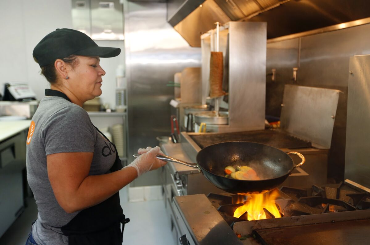 Clementina Munoz roasts vegetables at Daphne's in Mission Valley. The chain has eight restaurants in San Diego County with plans to open one in Escondido.