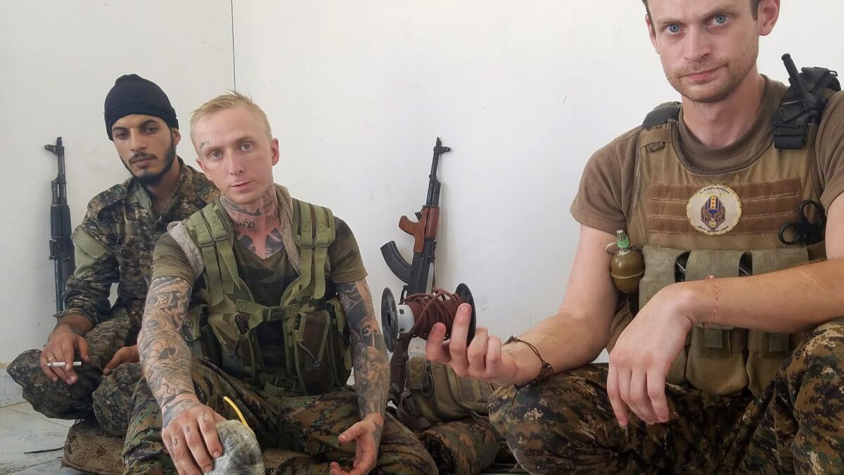 At their outpost in Raqqah, Syria, Syriac Military Council fighters Hasan Abja, Kevin Howard and Taylor Hudson display the homemade bomb and string they were issued to defuse mines.