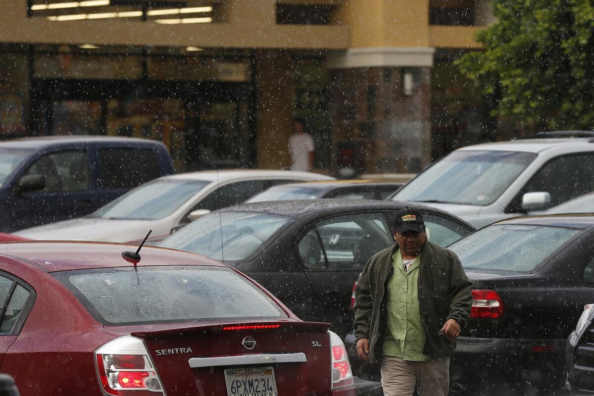 Rain pounds the parking lot of the College Center strip mall in Azusa earlier this year. Any rain Sunday is expected to be lighter.