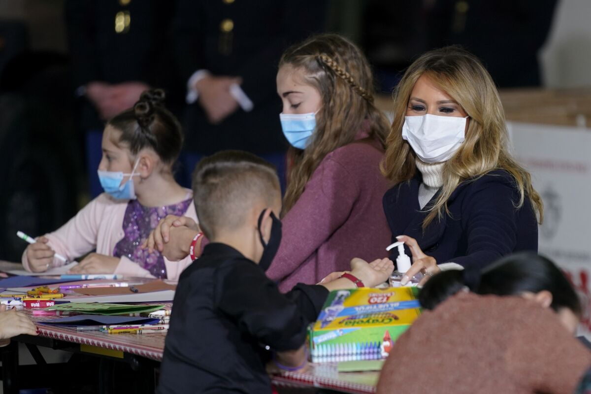 First lady Melania Trump offers hand sanitizer to a child as she participates in the U.S. Marine Corps Reserve's Toys for Tots Drive at Joint Base Anacostia-Bolling in Washington, Tuesday, Dec. 8, 2020. (AP Photo/Patrick Semansky)