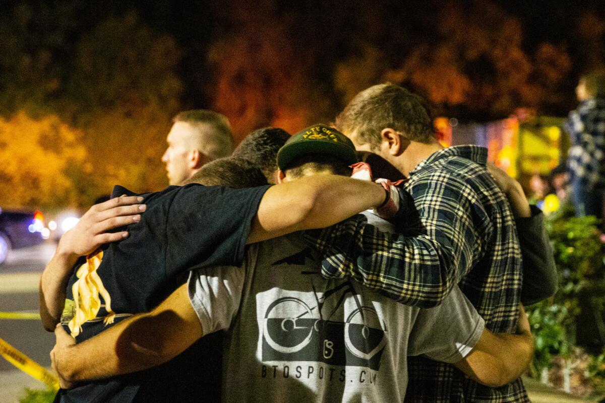 People huddle together in a parking lot along South Moorpark Road in the aftermath of a mass shooting at Borderline Bar & Grill.