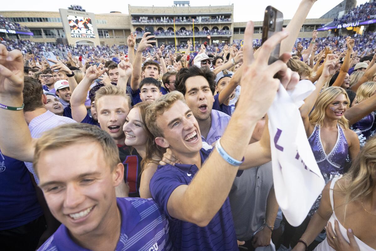 TCU fans celebrate on the field after their team defeated Oklahoma State in double overtime of an NCAA college football game in Fort Worth, Texas, Saturday, Oct. 15, 2022. TCU won 43-40. (AP Photo/Sam Hodde)
