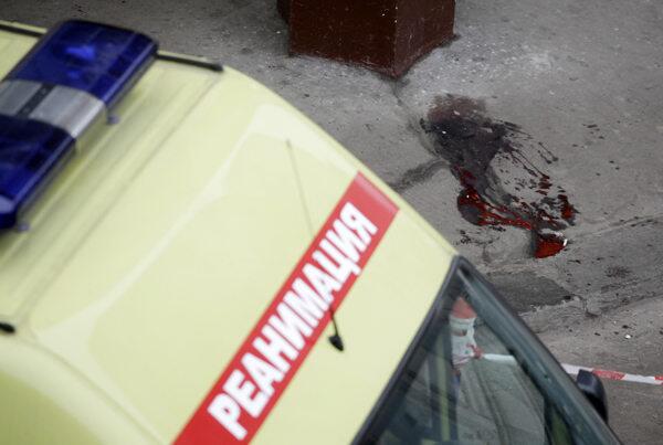 An ambulance sits parked near a puddle of blood