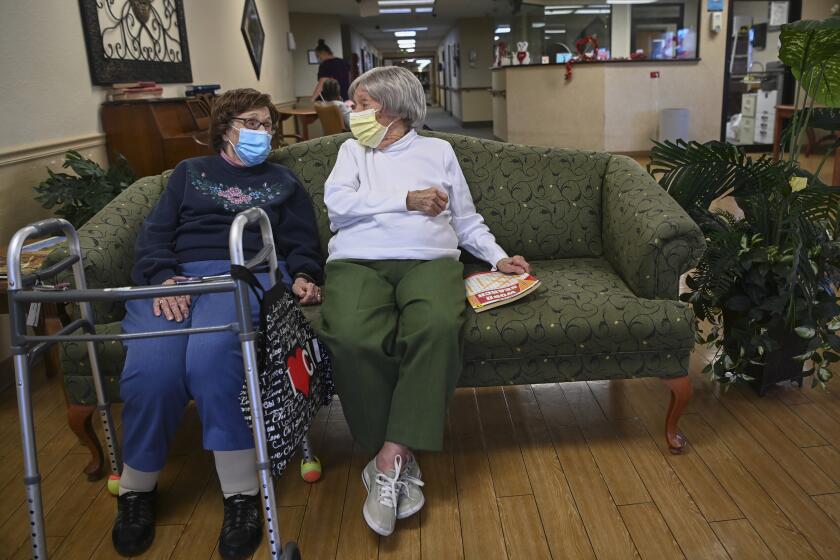 Carmela Sileo, left, and Susan McEachern sit next to each other and talk in the dayroom Wednesday, Feb. 3, 2021, at Arbor Springs Health and Rehabilitation Center in Opelika, Ala. Coronavirus cases have dropped at U.S. nursing homes and other long-term care centers over the past few weeks, offering a glimmer of hope that studies and health officials link to various factors, including the start of vaccinations, the easing of a post-holiday virus surge and better prevention. (AP Photo/Julie Bennett)