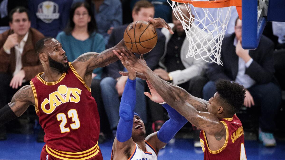 Knicks forward Carmelo Anthony puts up an awkward shot as he's defended by Cavaliers forward LeBron James (23) and guard Iman Shumpert during the first half Wednesday.