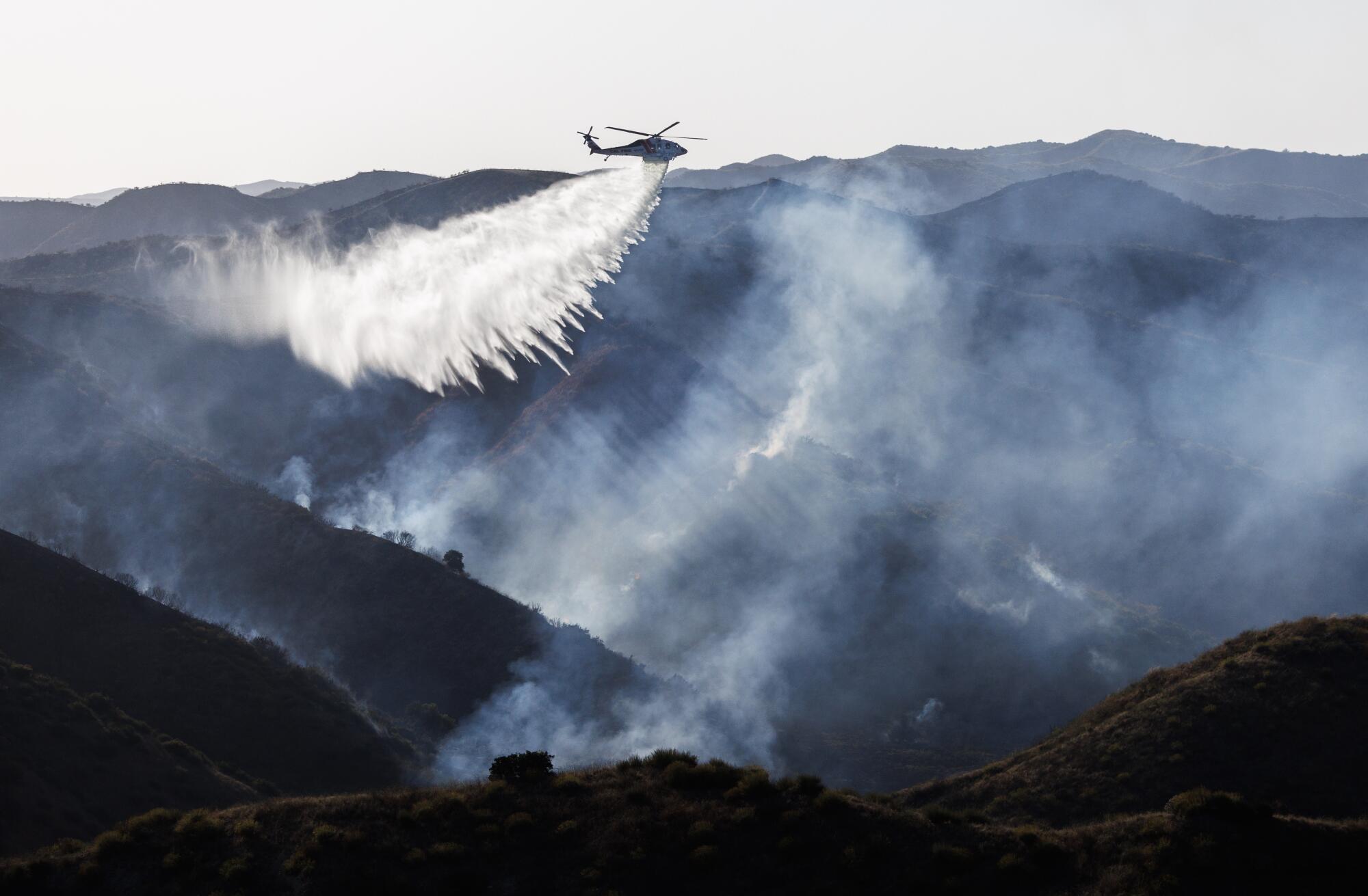CalFire drops water from a helicopter to battle the wind driven Lisa fire from the air.