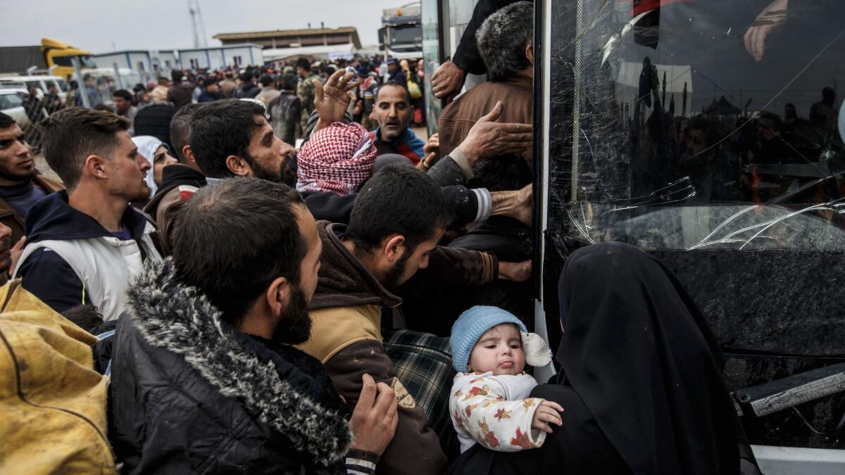 Civilians fleeing Mosul try to push their way onto a bus headed for another displaced persons camp outside of Hammam al-Alil.