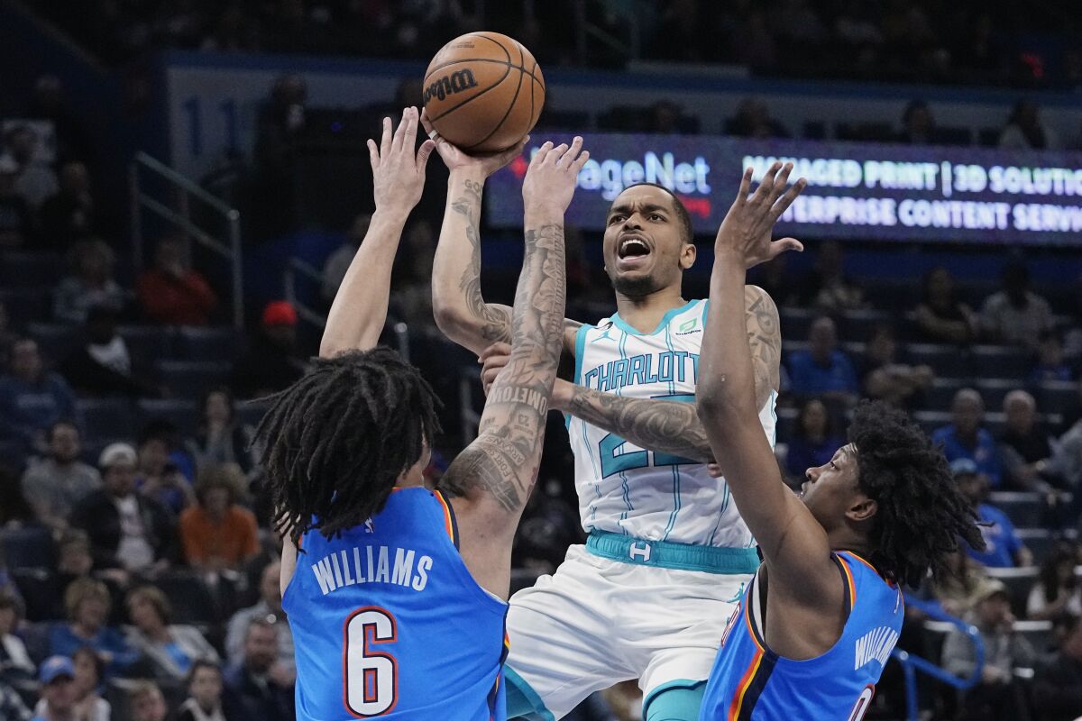 Charlotte Hornets forward P.J. Washington (25) shoots in front of Oklahoma City Thunder forward Jaylin Williams (6) and forward Jalen Williams, right, in the first half of an NBA basketball game Tuesday, March 28, 2023, in Oklahoma City. (AP Photo/Sue Ogrocki)