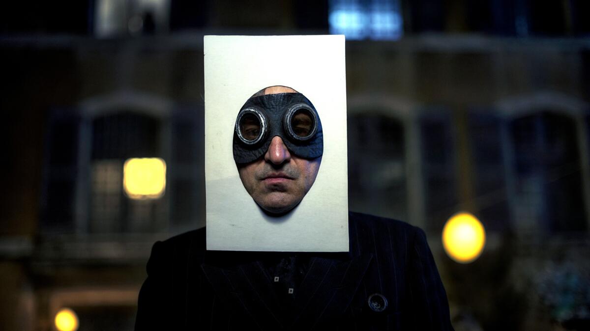 A man wears goggles and a rectangle of plain paper framing his face.
