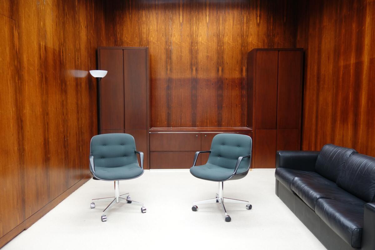 A partially empty office is lined in shimmering hard wood walls redolent of the Mad Men era.