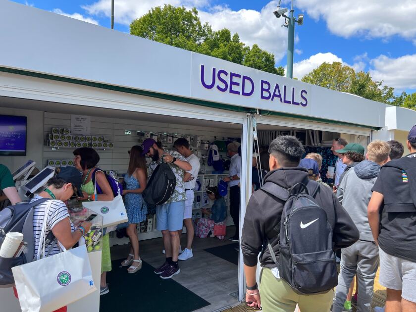 Fans gather at Wimbledon at a booth that sells tennis balls used for matches
