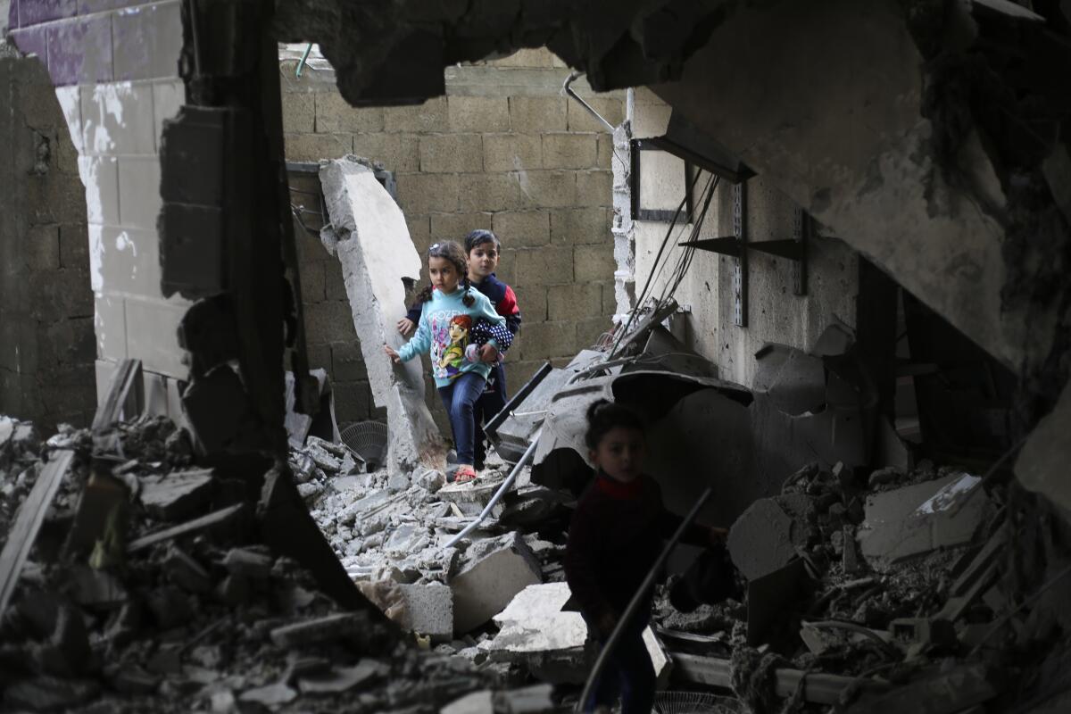 Children stand amid blasted-out walls and piles of rubble 