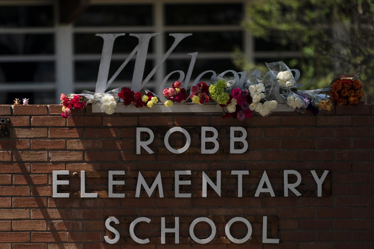 Flowers are placed around a welcome sign outside Robb Elementary School