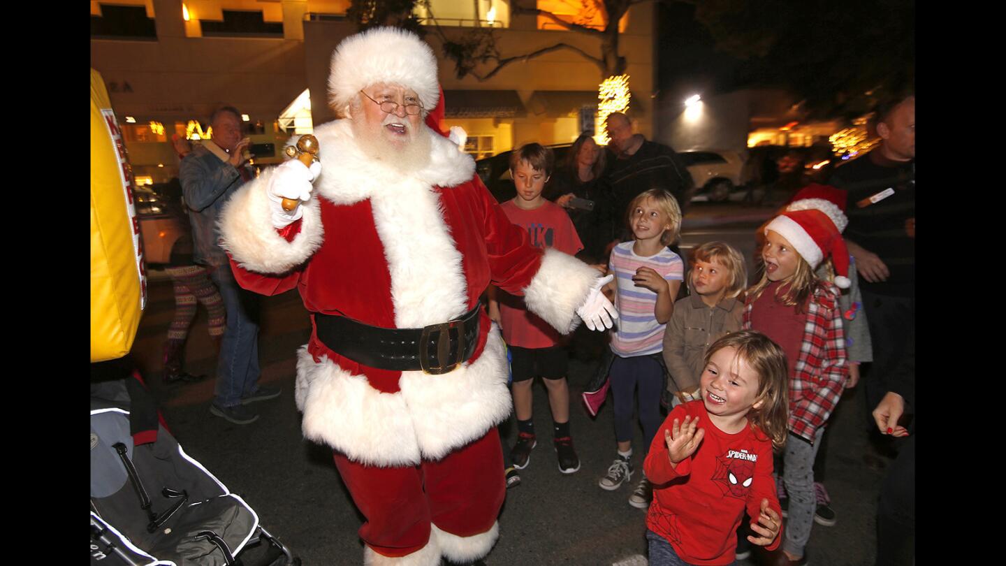 Kids get a glimpse of Santa Claus as he arrives to the 2017 Hospitality Night in the Pepper Tree Lot in downtown Laguna Beach.