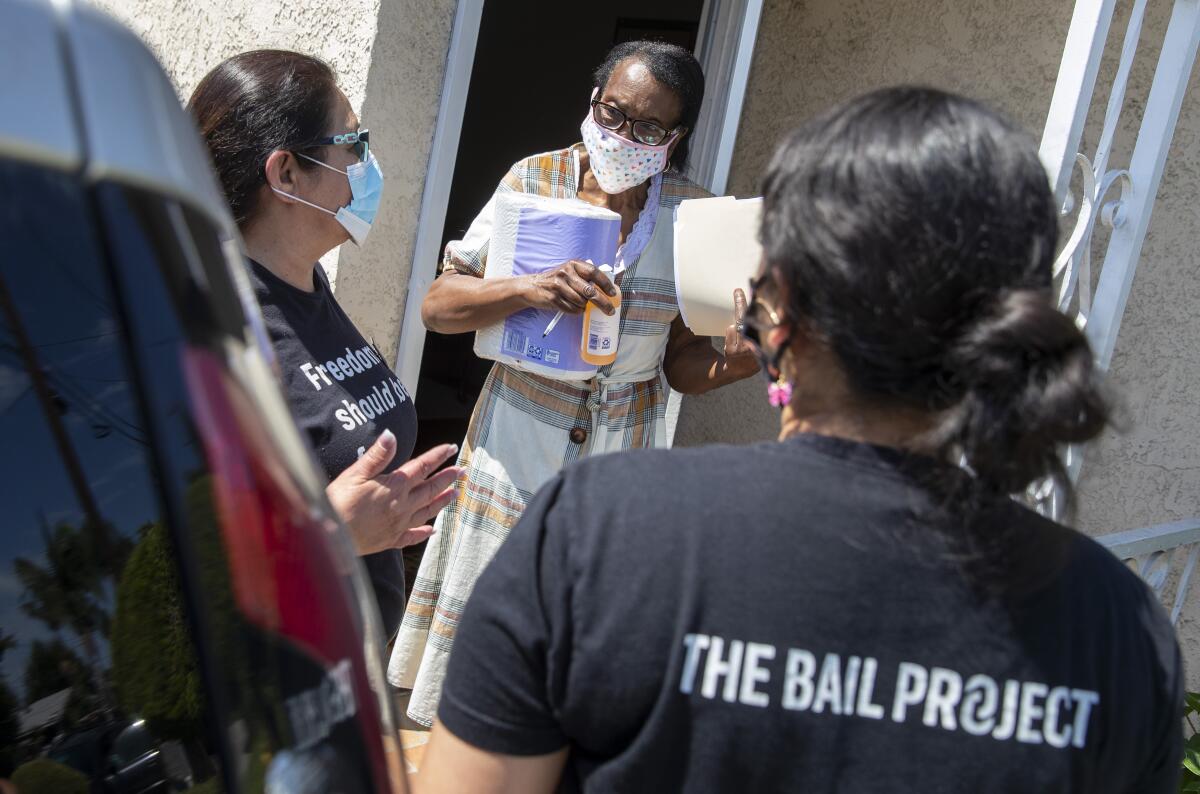 Susie Alexander, center, holds household supplies delivered for her son by Bail Project employees.