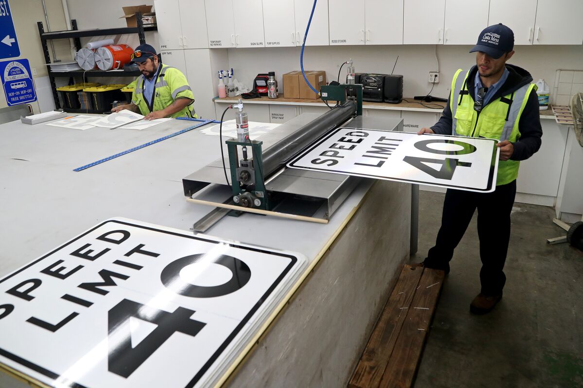 Maintenance worker Daniel Solis, right, and acting maintenance technician Henry Granados make new speed limit signs Tuesday.