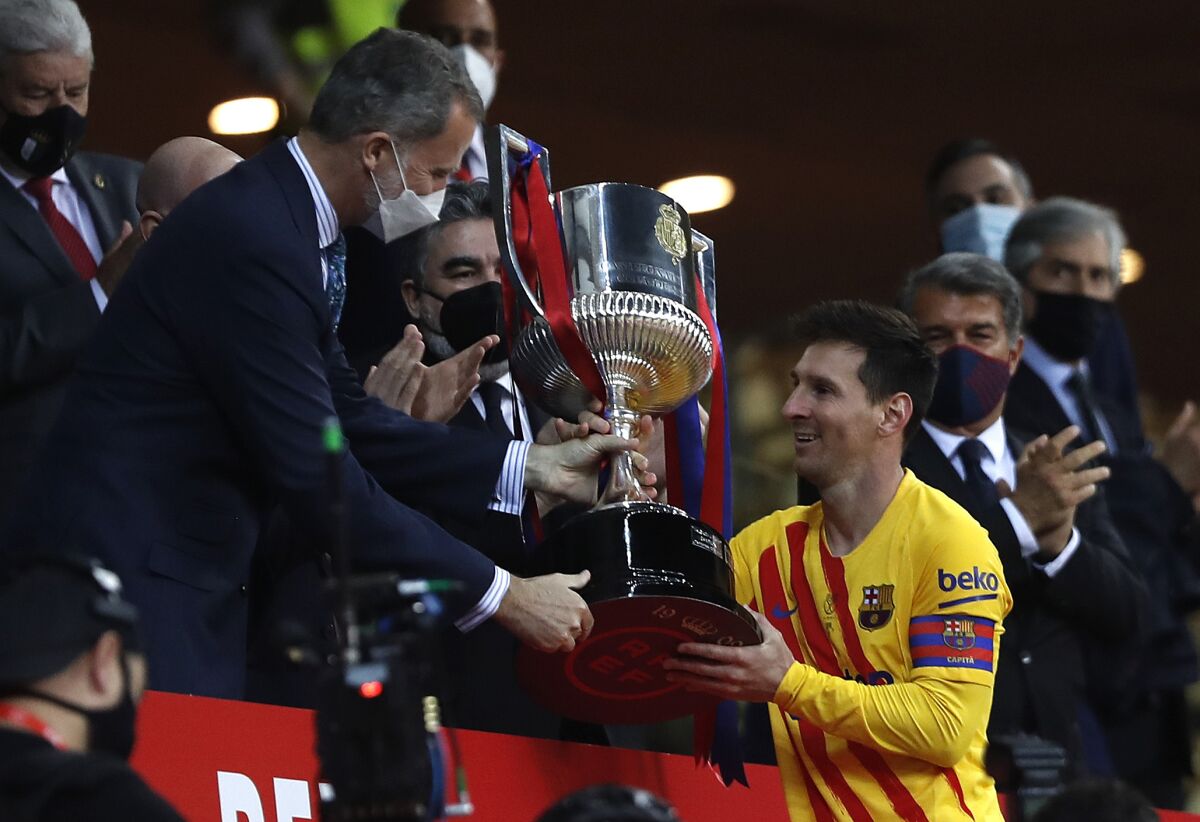 Barcelona's Lionel Messi receives the trophy by Spain's King Felipe after winning the Spanish Copa del Rey final 2021 against Athletic Bilbao at La Cartuja stadium in Seville, Spain, Saturday April 17, 2021. (AP Photo/Angel Fernandez)