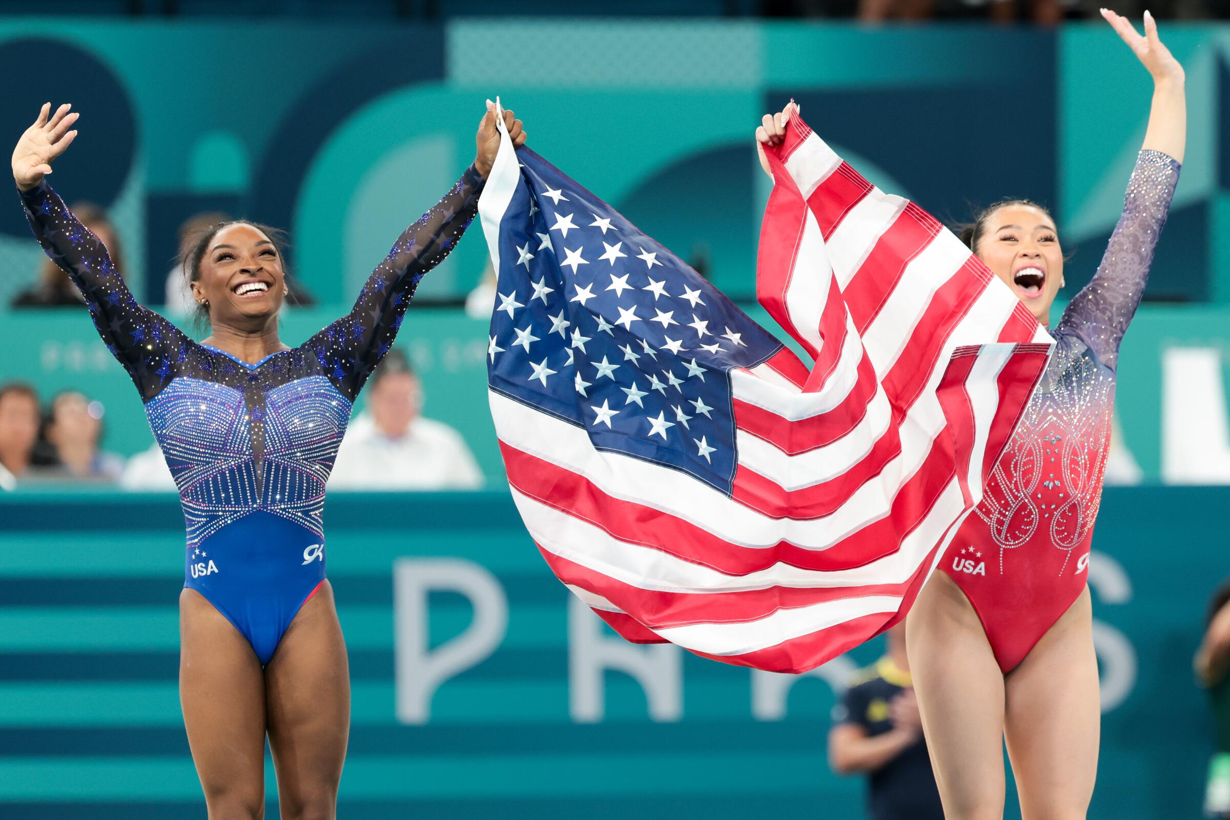U.S. teammates Simone Biles and Suni Lee hold up an American flag and wave after Biles won gold and Lee won silver 