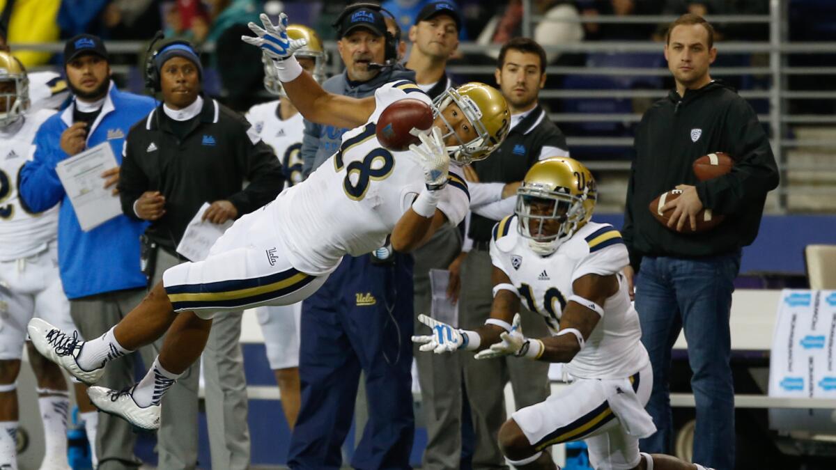 UCLA wide receiver Thomas Duarte, left, makes a diving catch in front of teammate Kenneth Walker III during the Bruins' 44-30 win over Washington on Saturday.