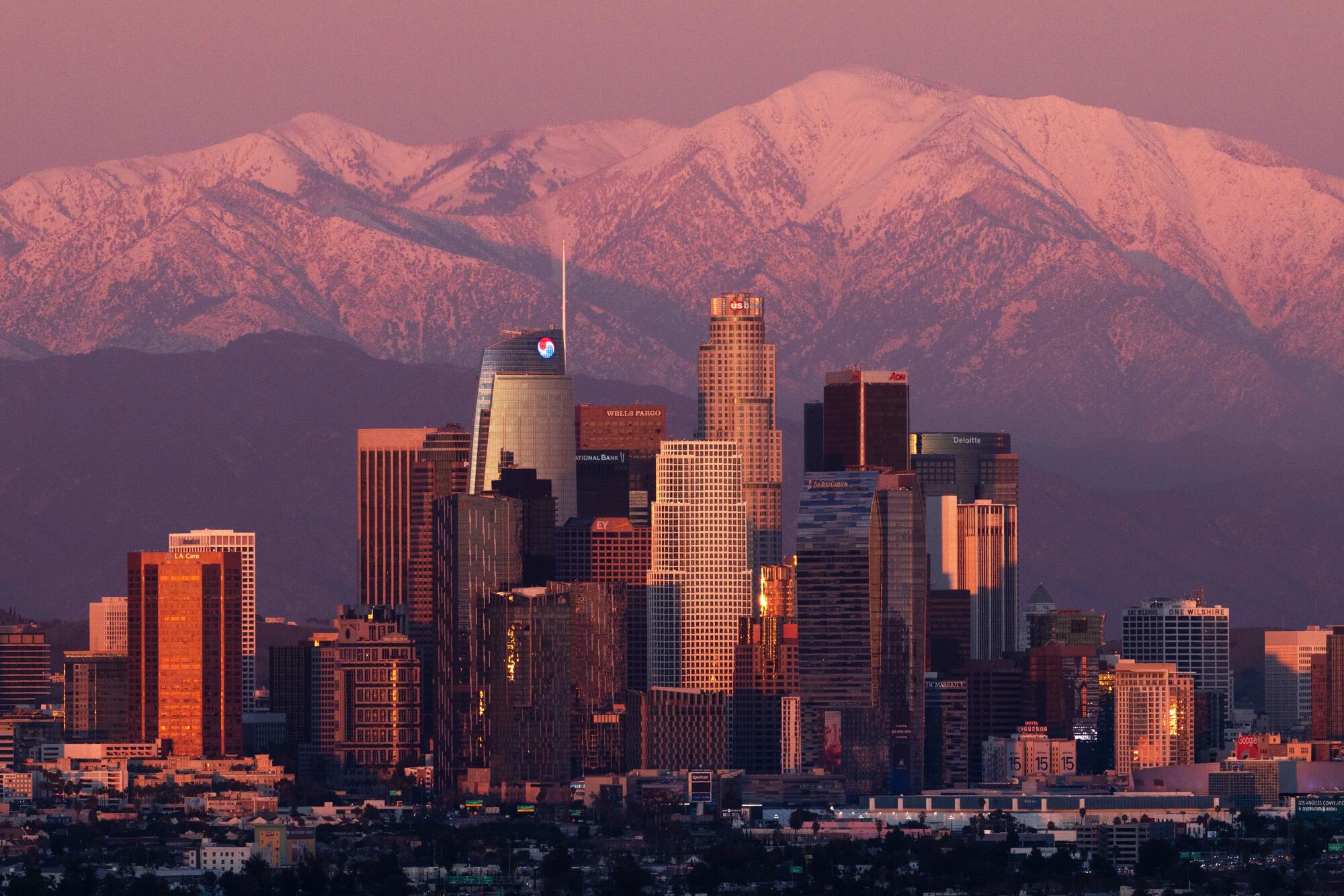 Snow-covered mountains glow pink in the sunset.