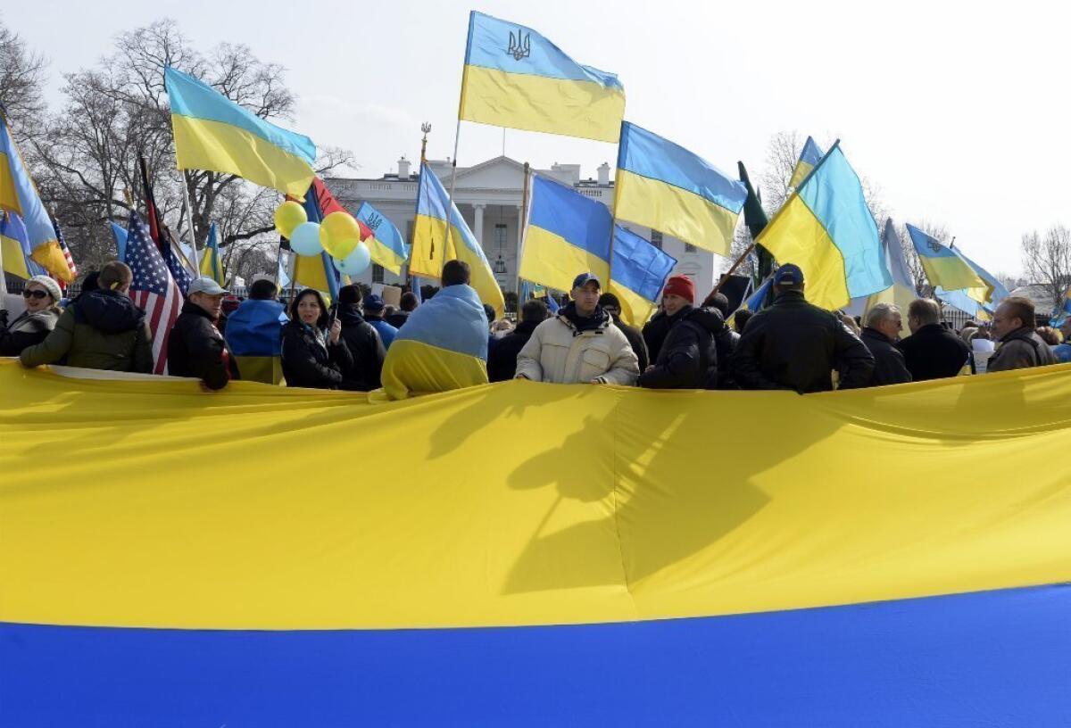 Demonstrators hold a large national flag of Ukraine during a rally to support Ukraine and denounce Russia outside the White House on Thursday. President Obama has said that a proposed referendum in Crimea would violate the Ukrainian constitution and international law.