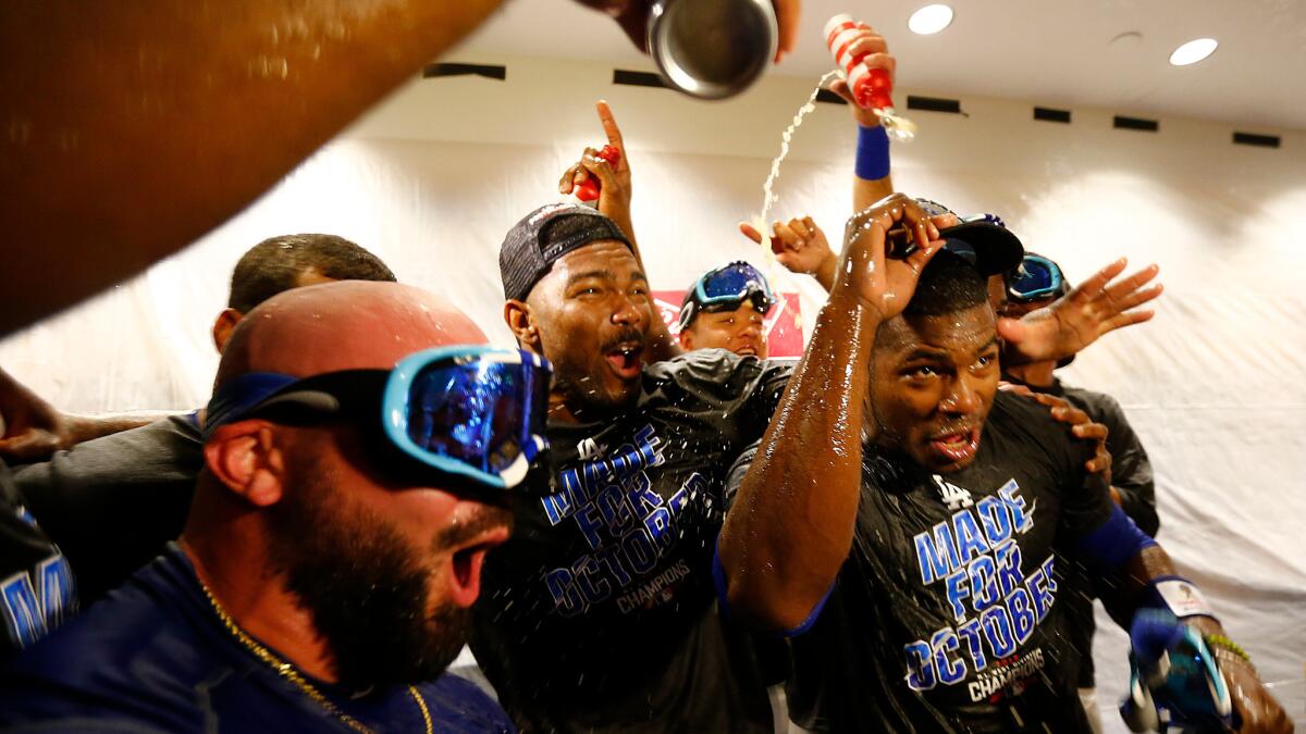 Right fielder Yasiel Puig, right, celebrates in the locker room with teammates after the Dodgers clinched the National League West title.