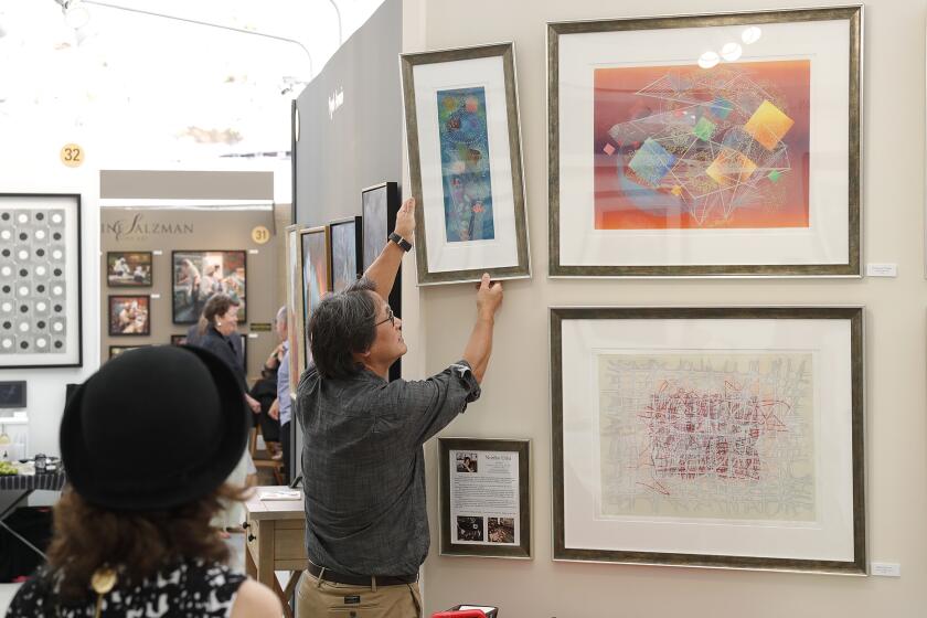 Printmaker Noriho Uriu watches as her assistant hangs a print on her display wall on opening day of the of the Festival of Arts Show in Laguna Beach on Saturday.