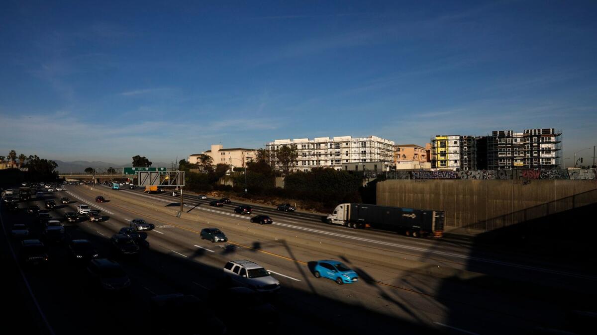 Traffic flows below a pair of housing developments being built next to the 110 Freeway at El Segundo Boulevard.