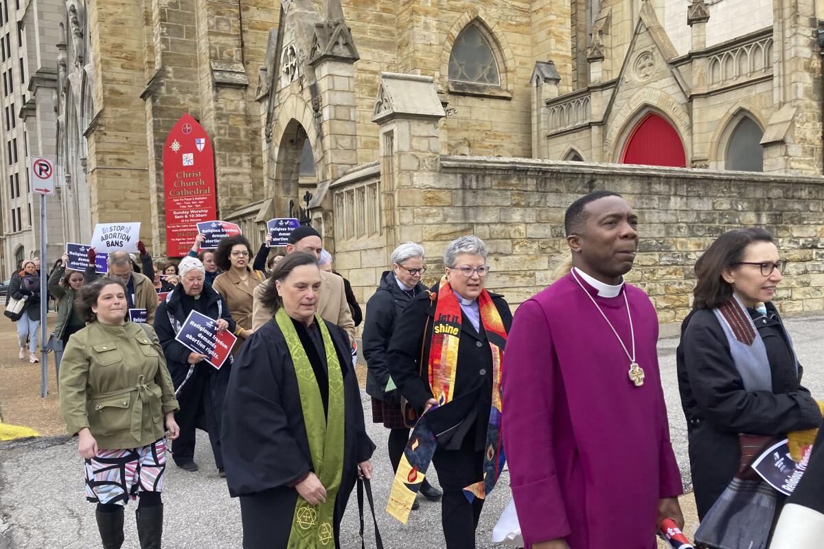 Religious leaders march past a church holding signs