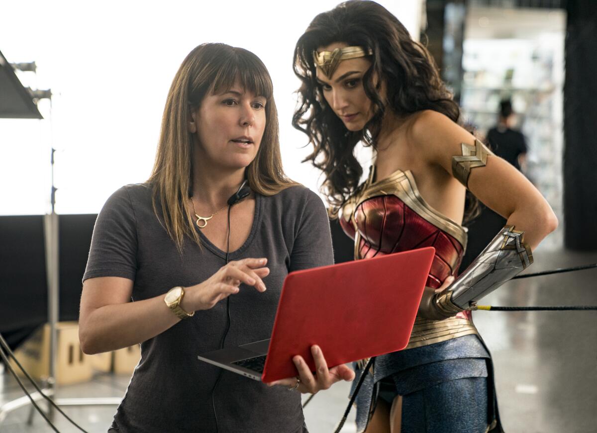 Patty Jenkins looks at a laptop with with Gal Gadot, in costume as Wonder Woman.