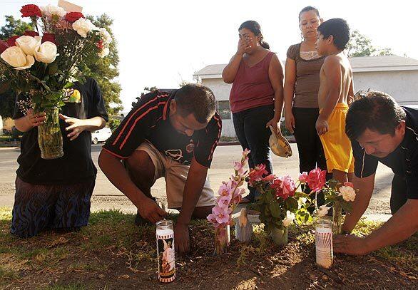 Members of the community place flowers and candles at the site of the shooting near Aragon Avenue and Thorpe Avenue in Cypress Park.