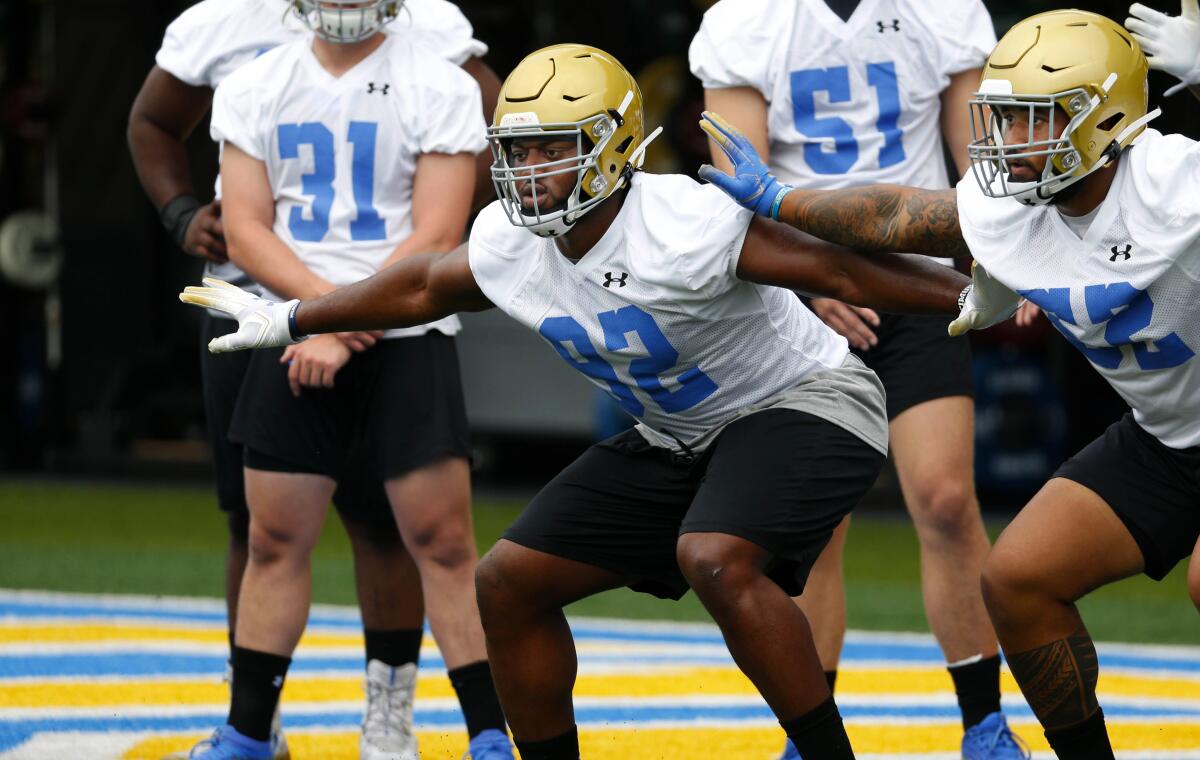 UCLA defensive lineman Osa Odighizuwa, left, takes part in drills at training camp.