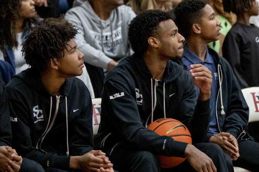 Sierra Canyon standout Bronny James, middle, watches from the bench during a game against Harvard-Westlake on Jan. 20, 2023.