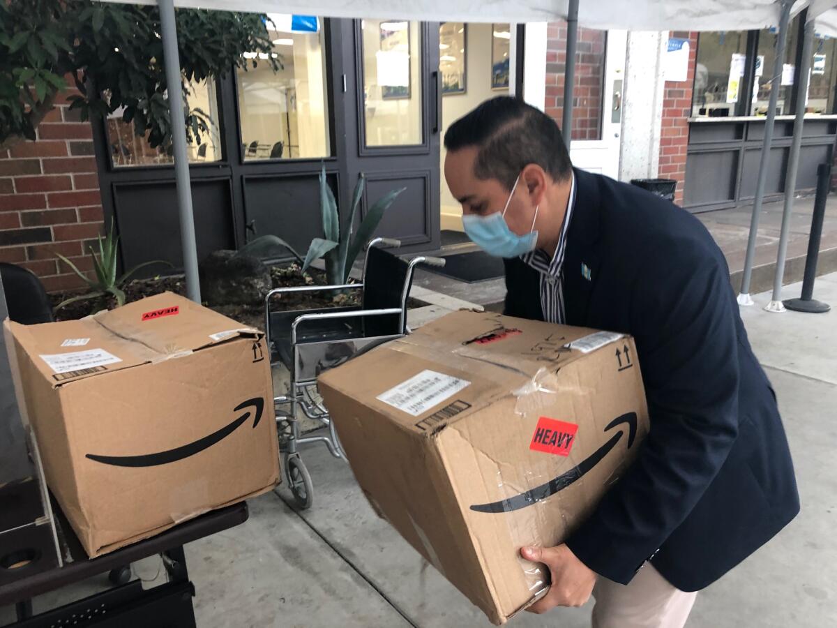 El cónsul guatemalteco en Los Ángeles, Tekandi Paniagua, carga una caja con desinfectantes.
