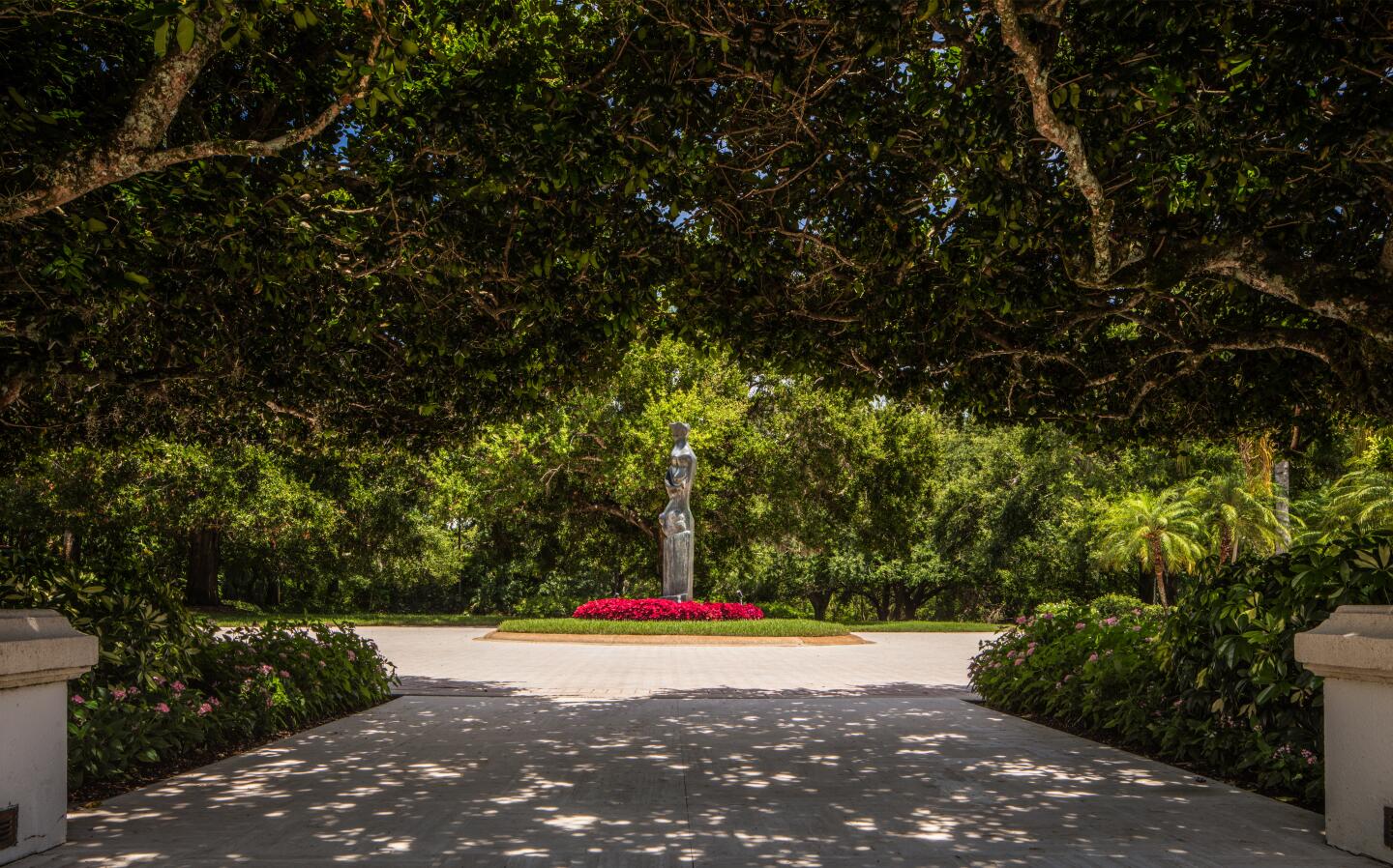 A statue surrounded by flowers is at the center of the circular driveway.