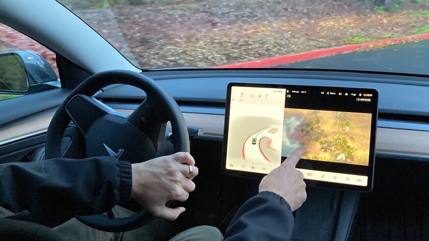 Vince Patton, a new Tesla owner, demonstrates on Wednesday, Dec. 8, 2021, on a closed course in Portland, Ore., how he can play video games on the vehicle's console while driving. Patton, of Portland, Ore., filed a complaint with federal regulators after discovering the feature in his new car. (AP Photo/Gillian Flaccus)