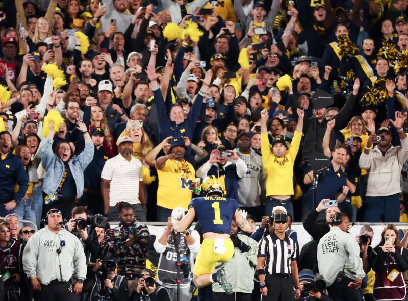 Michigan fans react as Wolverines wide receiver Roman Wilson leaps into the end zone to tie the game late in the fourth quarter.