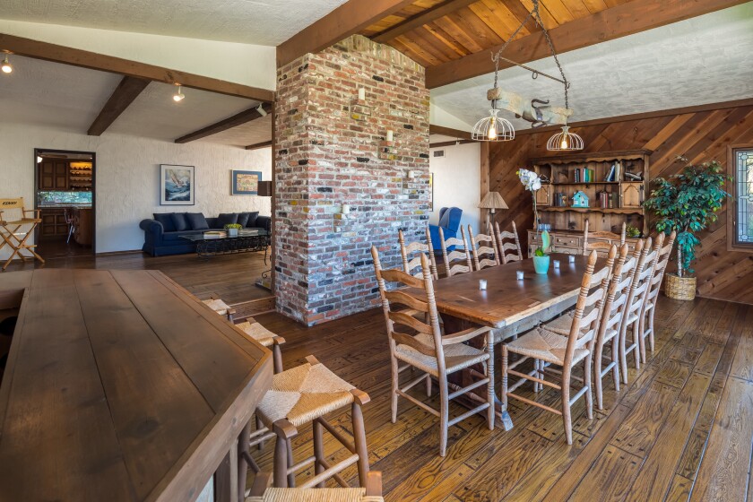 A brick fireplace separates the living room from the dining room of the rustic Studio City house.