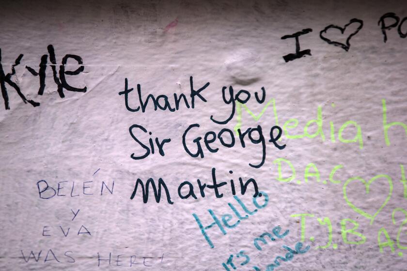 A message in tribute to Beatles producer George Martin is seen on the wall of Abbey Road Studios on Wednesday in London. Martin, who produced the Beatles, passed away Tuesday at 90.