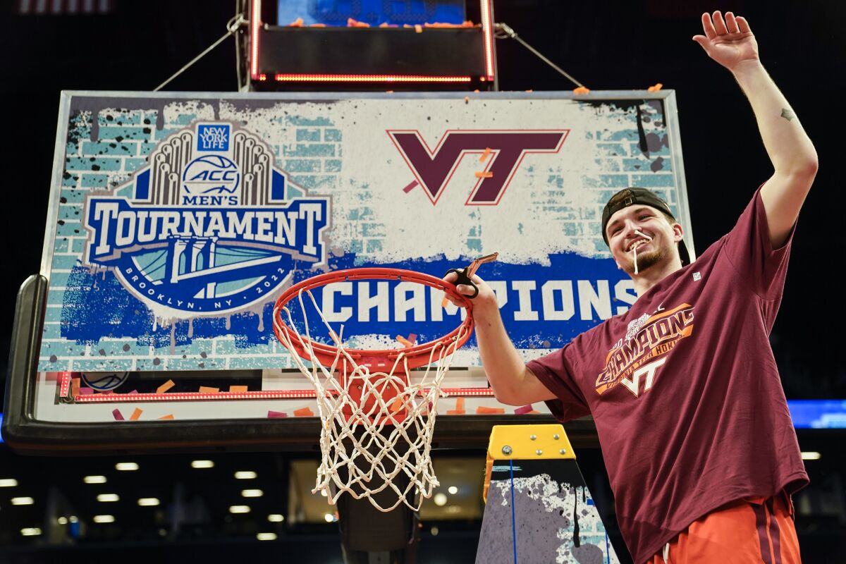 Virginia Tech's Hunter Cattoor, tournament most valuable player, celebrates with a piece of the game net after winning the NCAA college basketball championship game against Duke in the Atlantic Coast Conference men's tournament, Saturday, March 12, 2022, in New York. Virginia Tech won, 82-67. (AP Photo/John Minchillo)