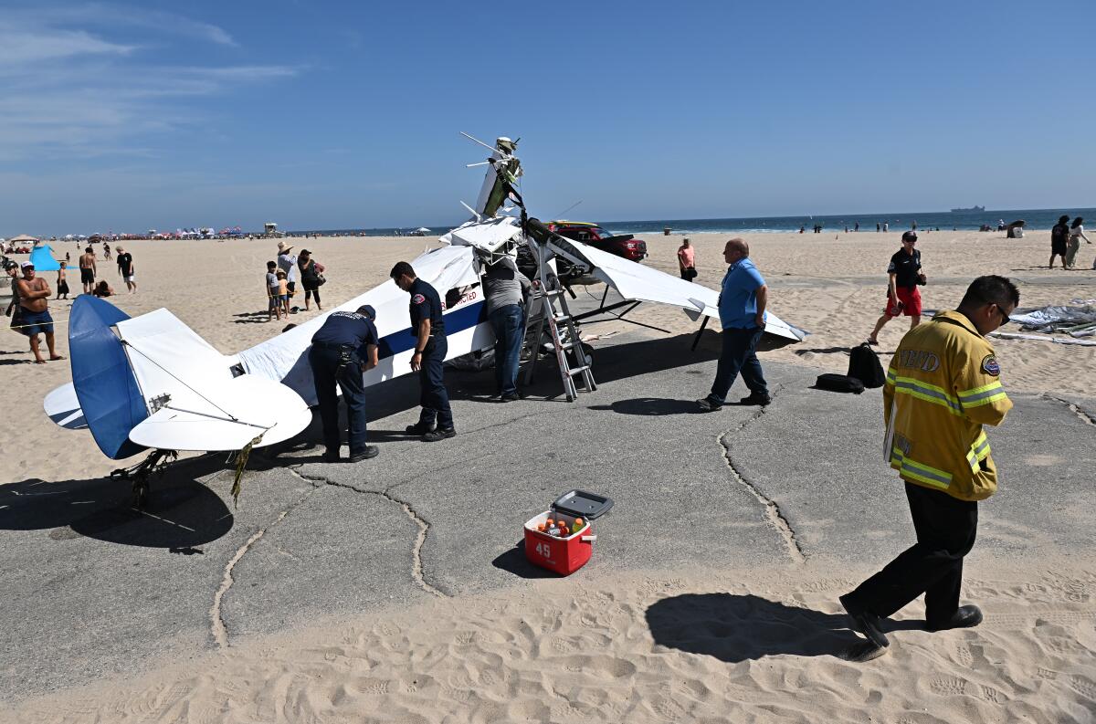 Officials inspect the damage from a plane that crashed into the water in Huntington Beach Friday.